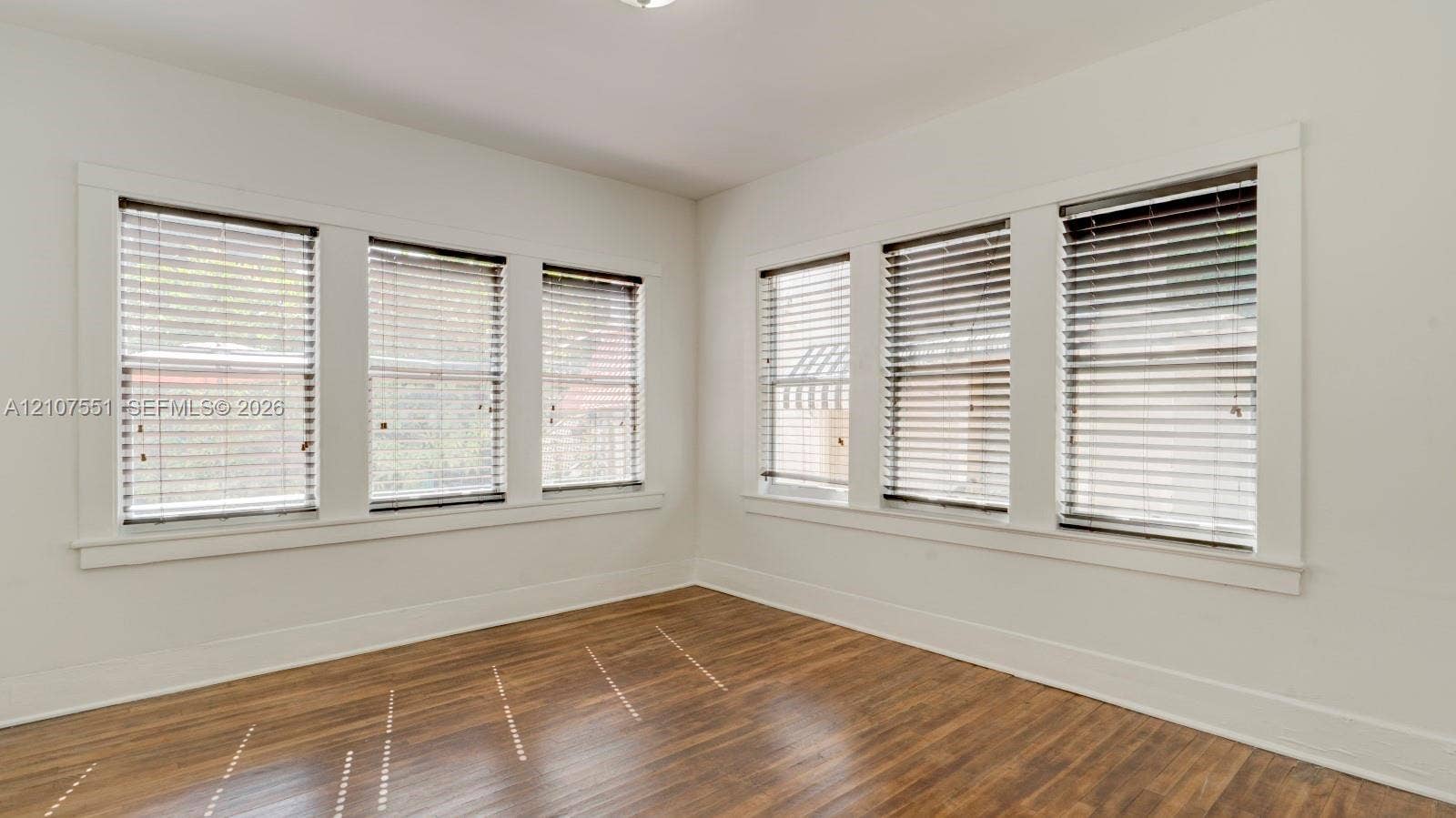 1676 SW 11th Street, Miami, Miami, FL 33135 Interior space featuring wood-finish flooring, six windows with horizontal blinds, and clean-lined white trim
