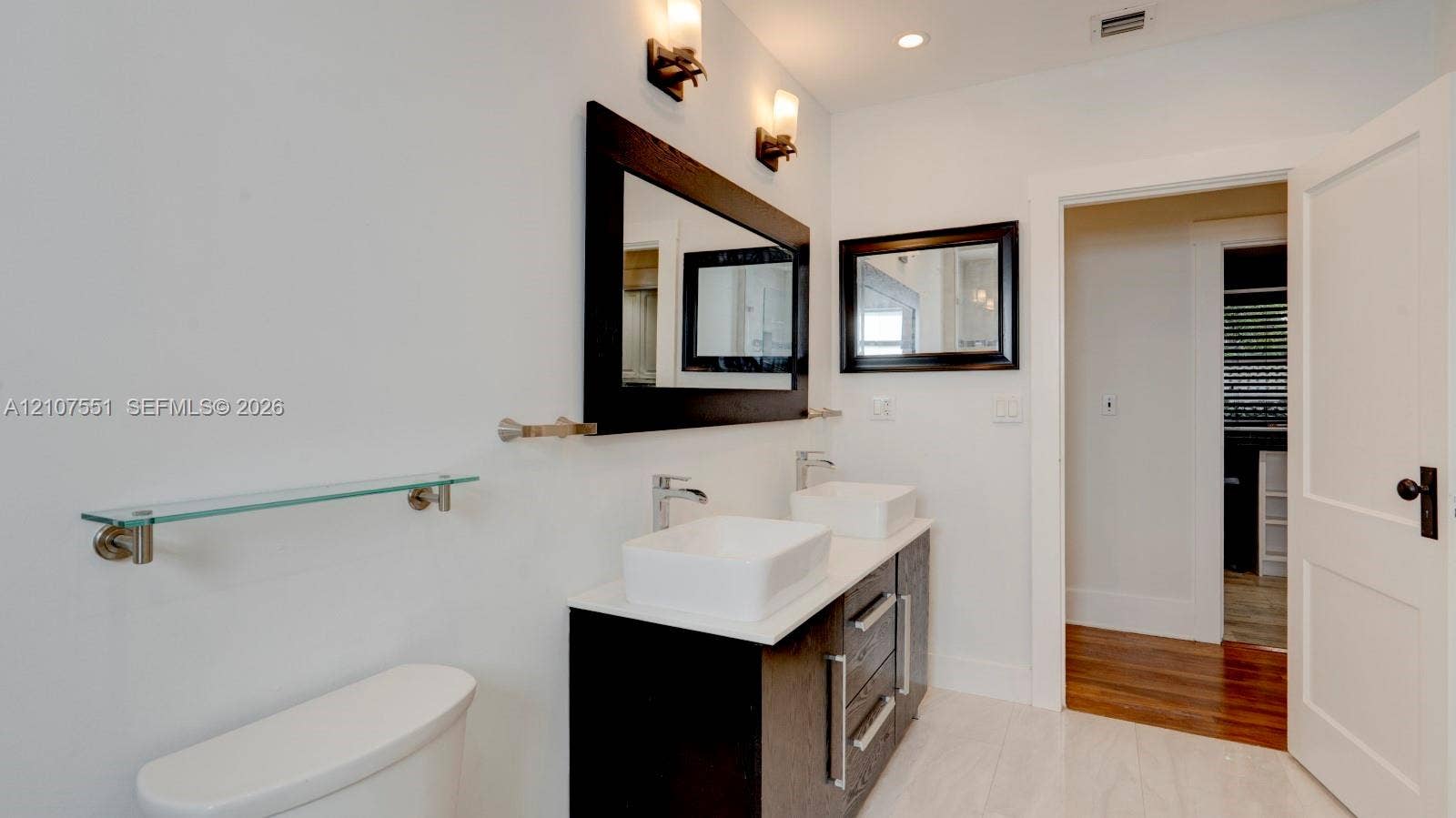 1676 SW 11th Street, Miami, Miami, FL 33135 Double vanity featuring rectangular vessel sinks, quartz countertops, dark-toned cabinetry, polished metal hardware, and dual wall-mounted mirrors