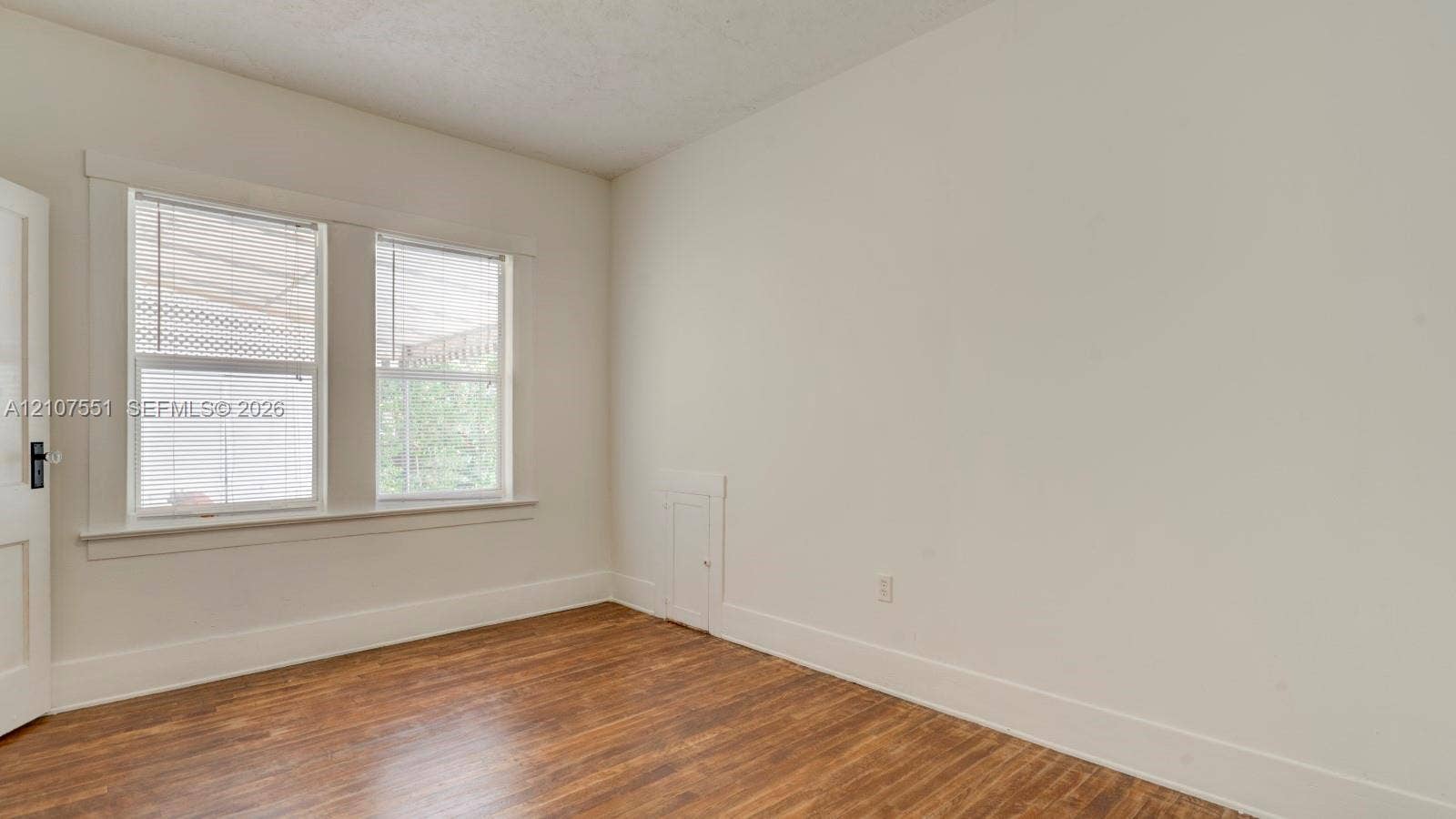 1676 SW 11th Street, Miami, Miami, FL 33135 Interior room featuring wood-finish flooring, dual windows with decorative millwork casing, and a built-in wall access panel
