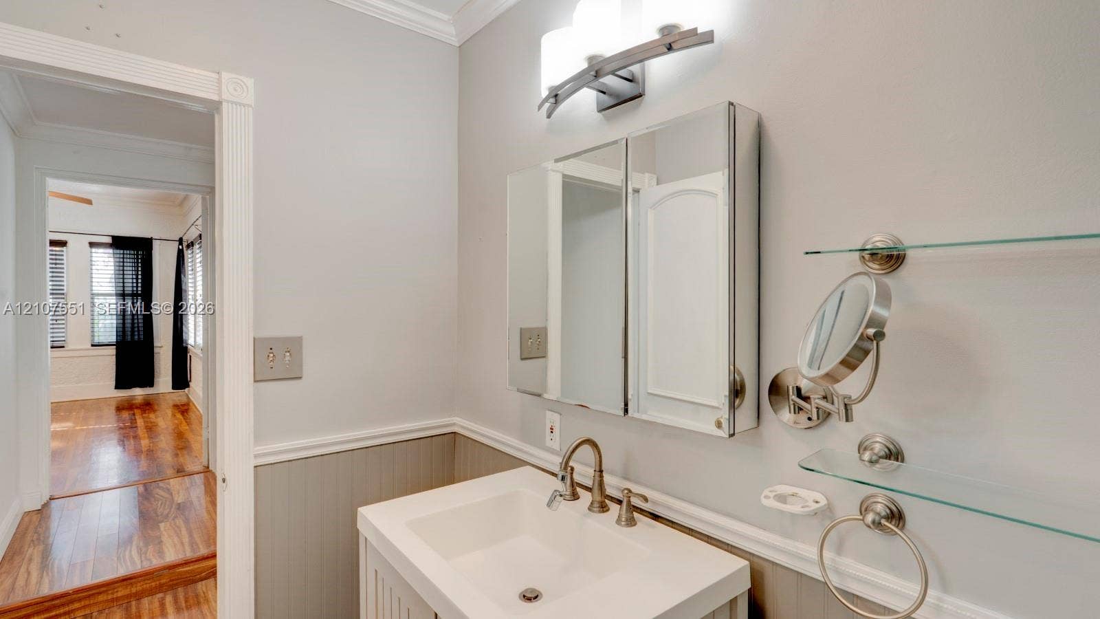 1676 SW 11th Street, Miami, Miami, FL 33135 Vanity featuring a rectangular basin, metallic faucet, mirrored medicine cabinet, wall-mounted glass shelving, and beadboard wainscoting