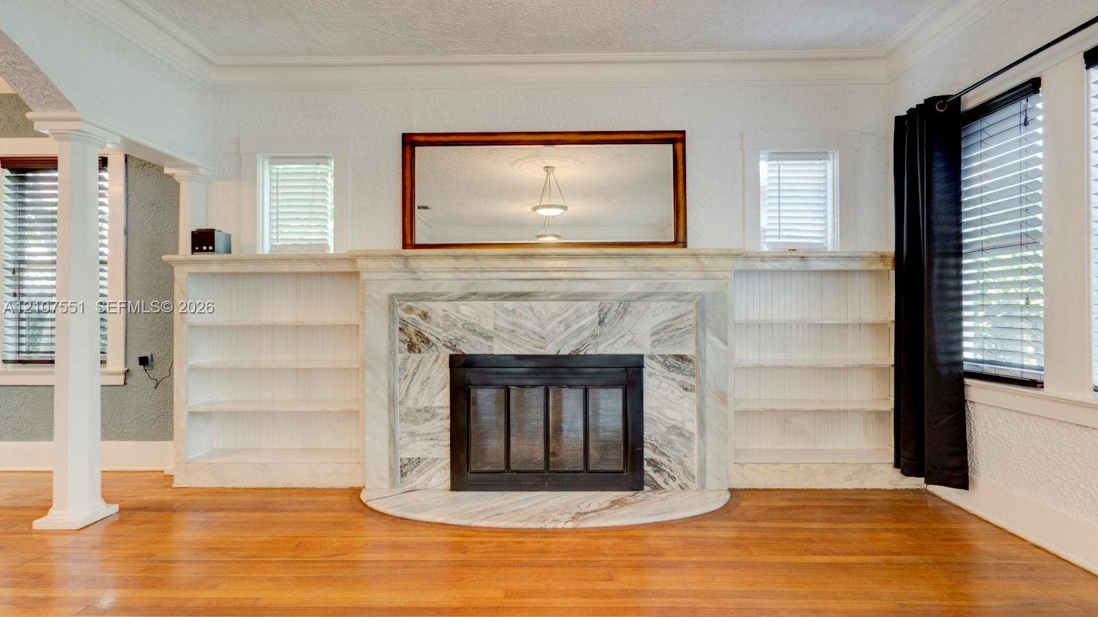 1676 SW 11th Street, Miami, Miami, FL 33135 Fireplace featuring a stone surround and hearth, flanked by symmetrical built-in shelving, complemented by wood-finish flooring and crown molding
