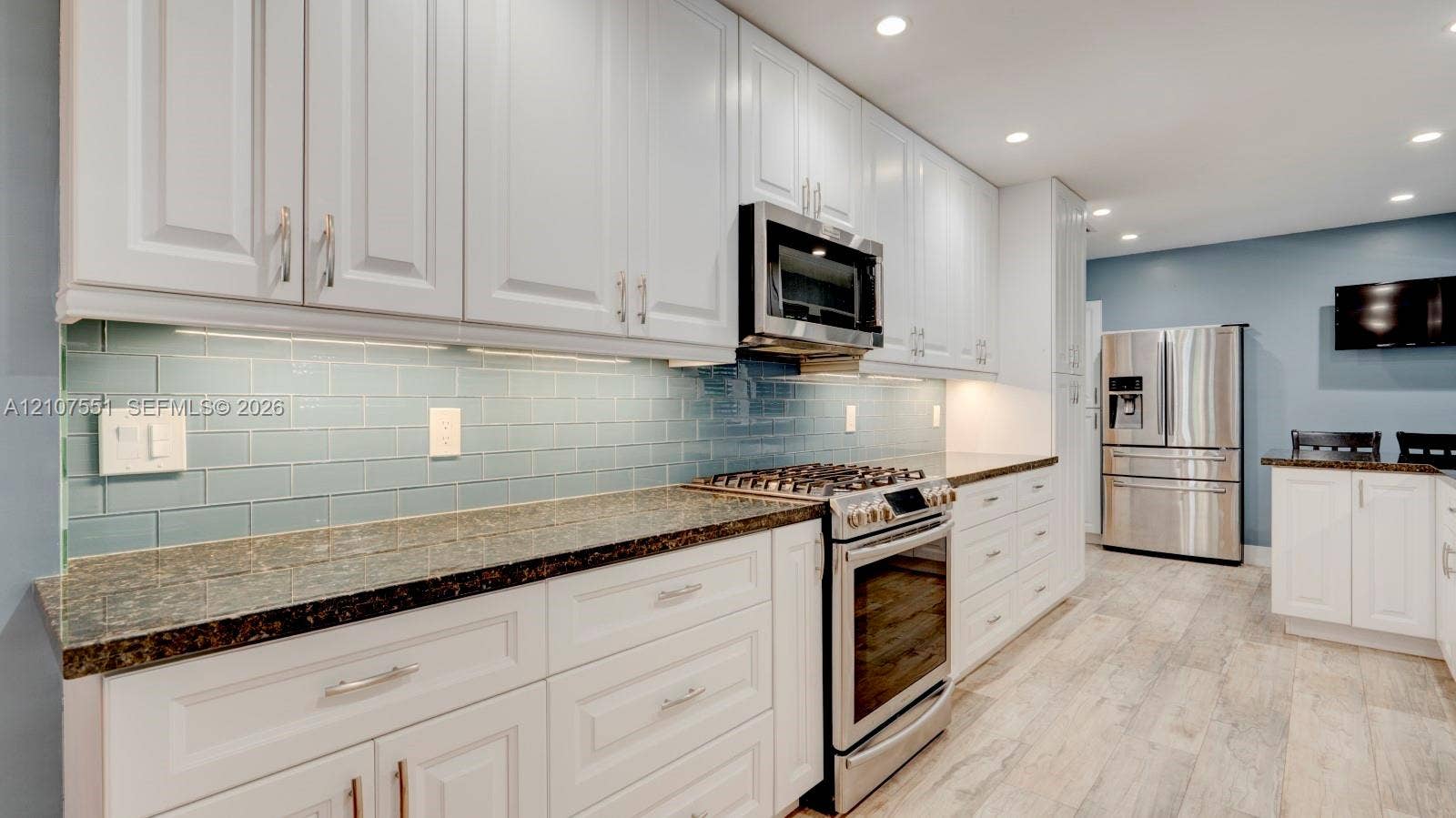 1676 SW 11th Street, Miami, Miami, FL 33135 Kitchen featuring white shaker-style cabinetry, stone countertops, a blue glass subway tile backsplash, stainless steel appliances, and wood-finish flooring