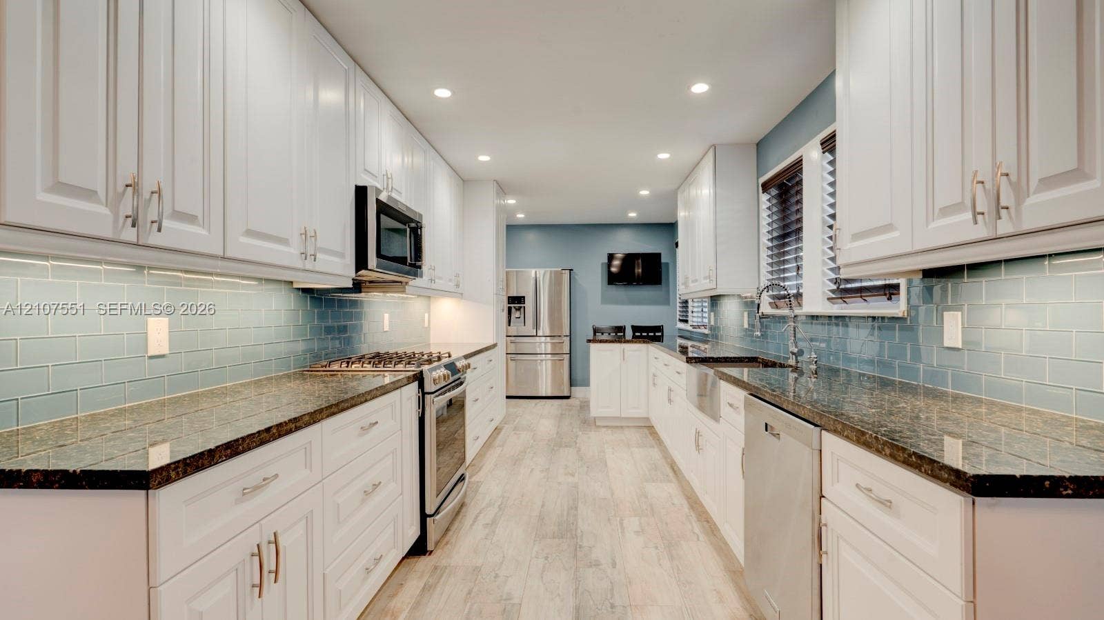 1676 SW 11th Street, Miami, Miami, FL 33135 Kitchen featuring shaker-style white cabinetry, dark stone countertops, blue subway tile backsplash, stainless steel appliances, and wood-finish flooring