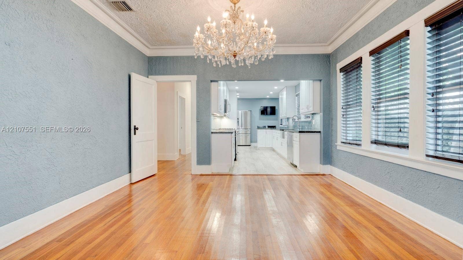 1676 SW 11th Street, Miami, Miami, FL 33135 Hardwood flooring, ornate crystal chandelier, textured walls, crown molding, and multi-pane windows with horizontal blinds