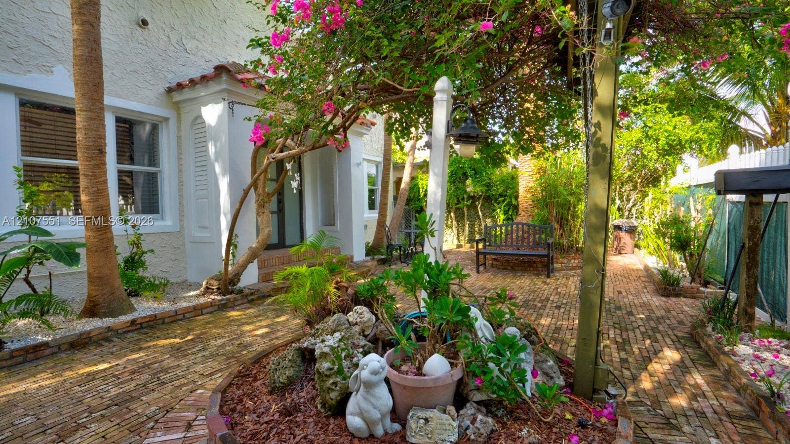 1676 SW 11th Street, Miami, Miami, FL 33135 Stucco exterior featuring brick-paved landscaping, a central garden bed, and a wooden arbor