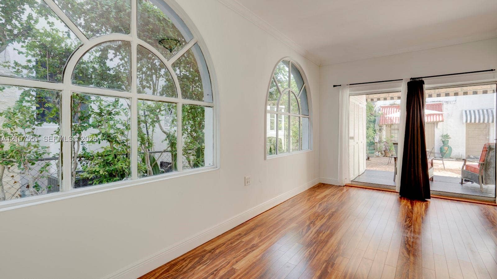 1676 SW 11th Street, Miami, Miami, FL 33135 Wood-finish flooring, large arched windows, and a sliding glass door providing access to an outdoor patio