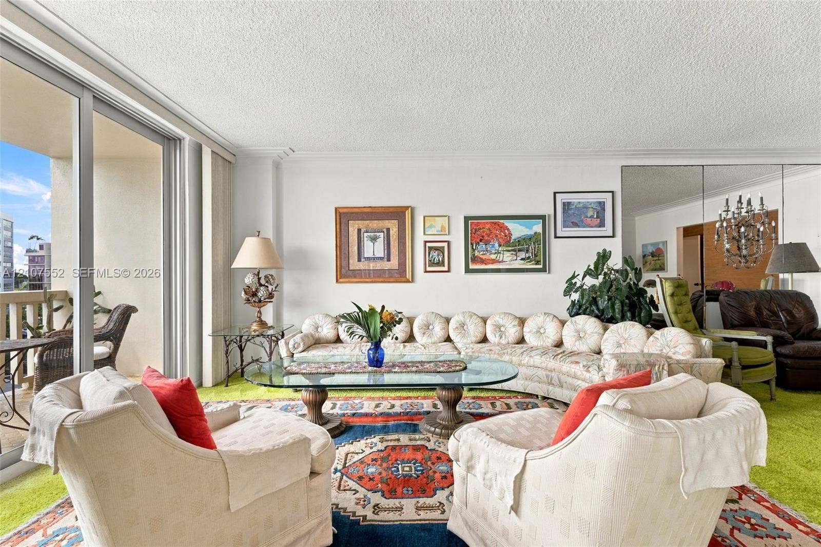 Living area featuring floor-to-ceiling glass sliding doors, private balcony access, and floor-to-ceiling mirrored wall panels