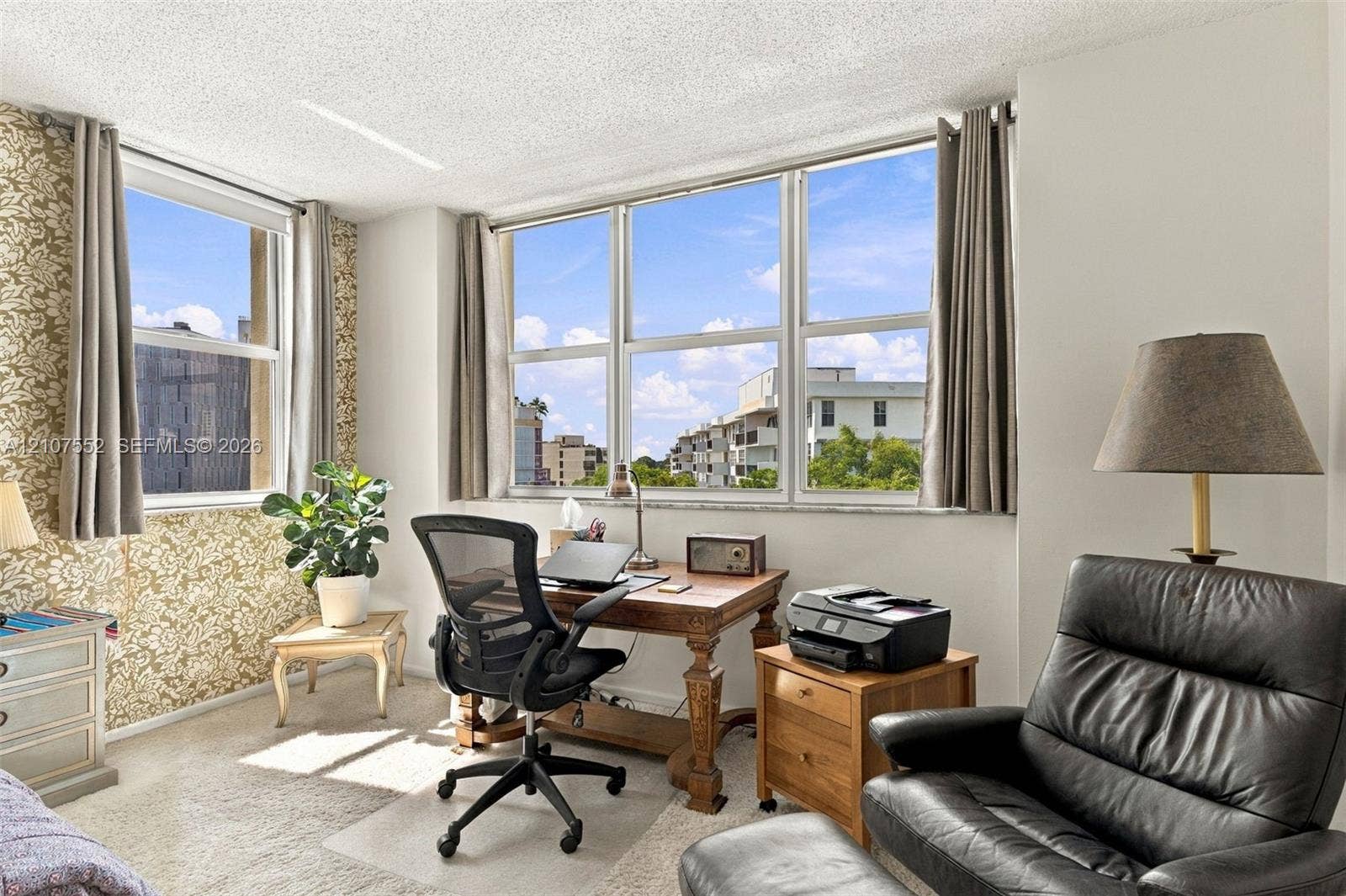 Room featuring large windows with natural light, patterned wall covering, and neutral carpeting