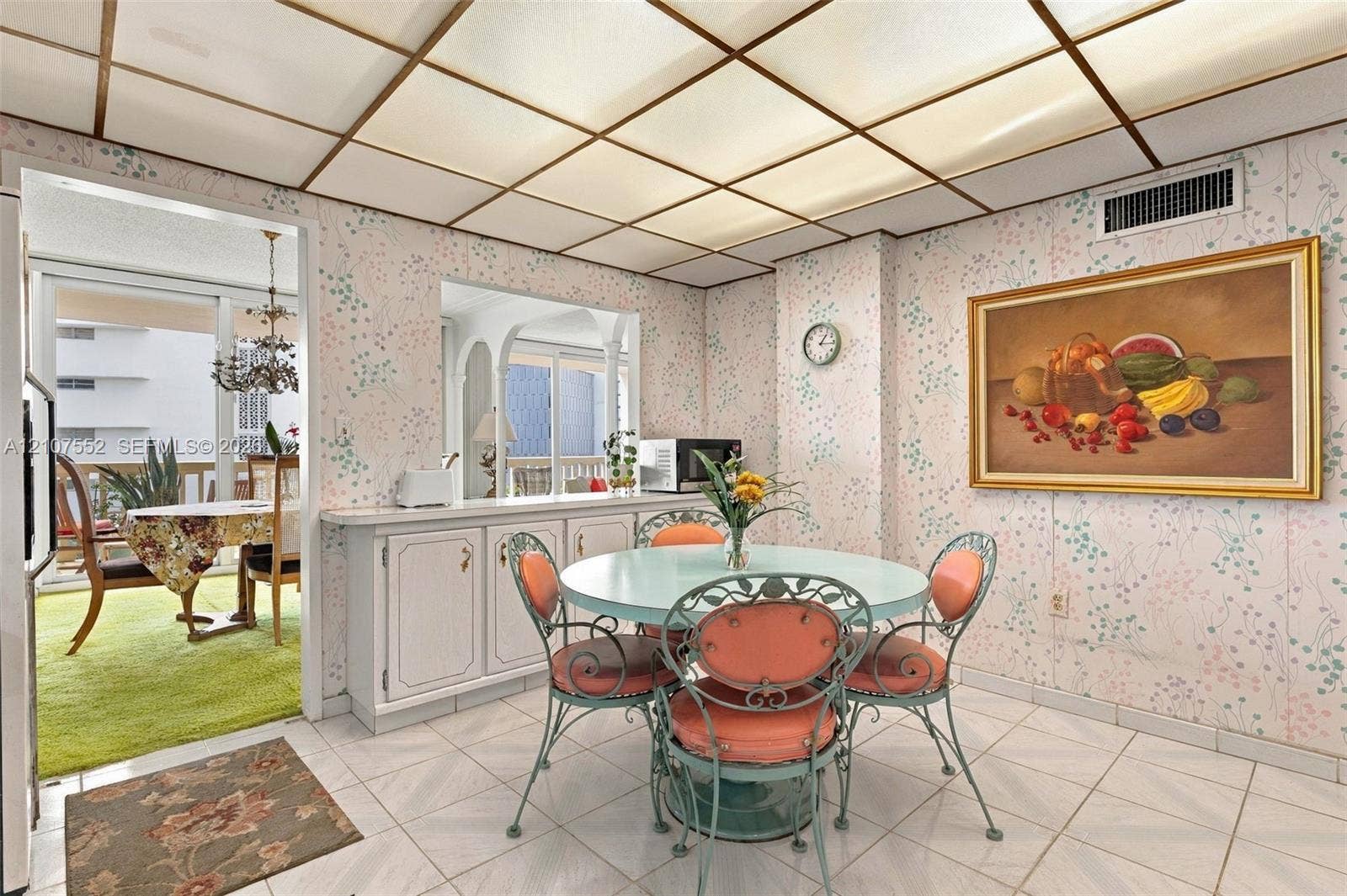 Grid-patterned drop ceiling with integrated lighting, ceramic tile flooring, and built-in cabinetry featuring a countertop pass-through