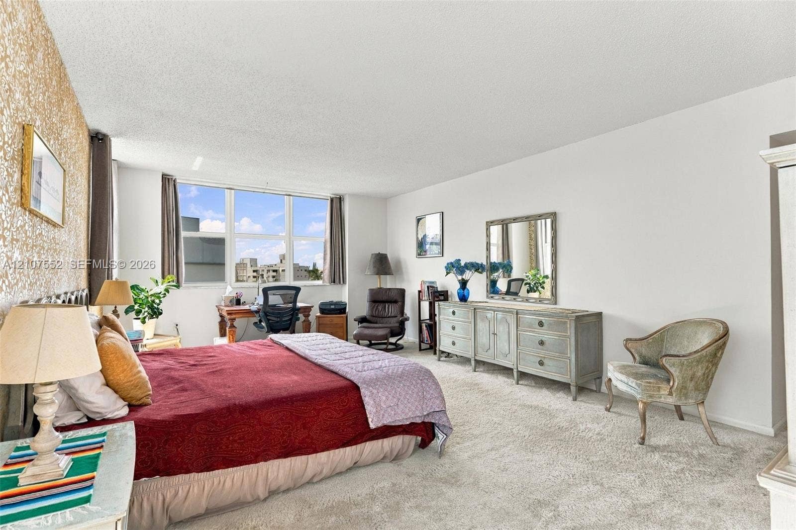 Neutral-toned carpeting, textured wall covering, and large windows providing natural light