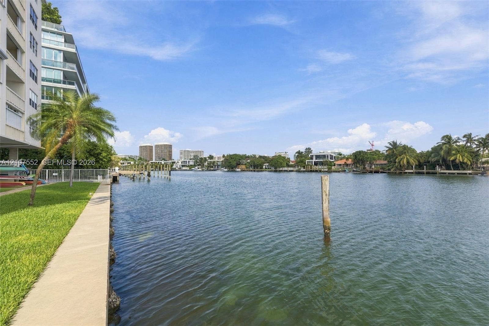 Waterfront property featuring a concrete seawall, manicured lawn, and multi-level building exterior