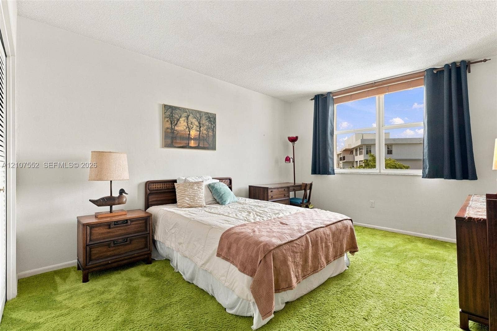 Spacious room featuring neutral wall tones, textured ceiling, and a large window providing natural light