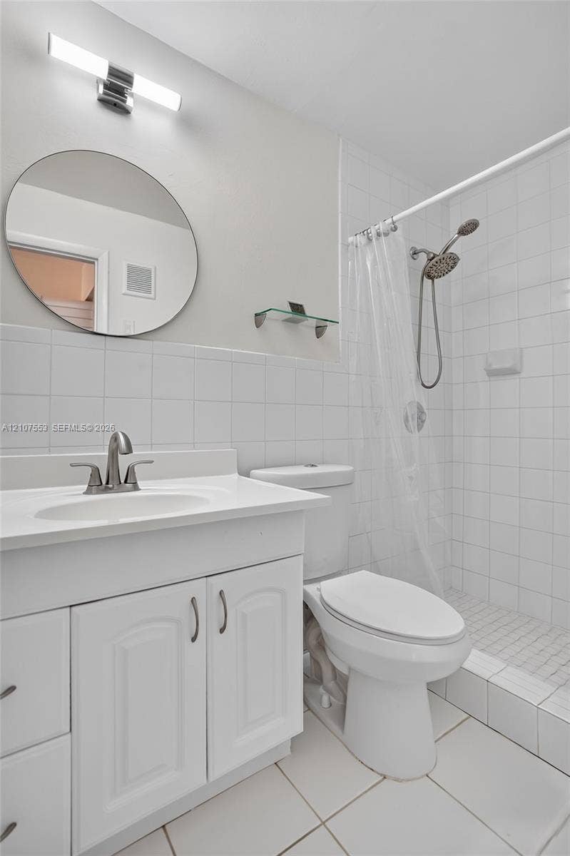 7336 SW 26th Court, #51, Davie, Davie, FL 33314 Bathroom featuring a vanity with integrated sink, circular wall-mounted mirror, modern light fixture, and tiled walk-in shower with adjustable handheld showerhead