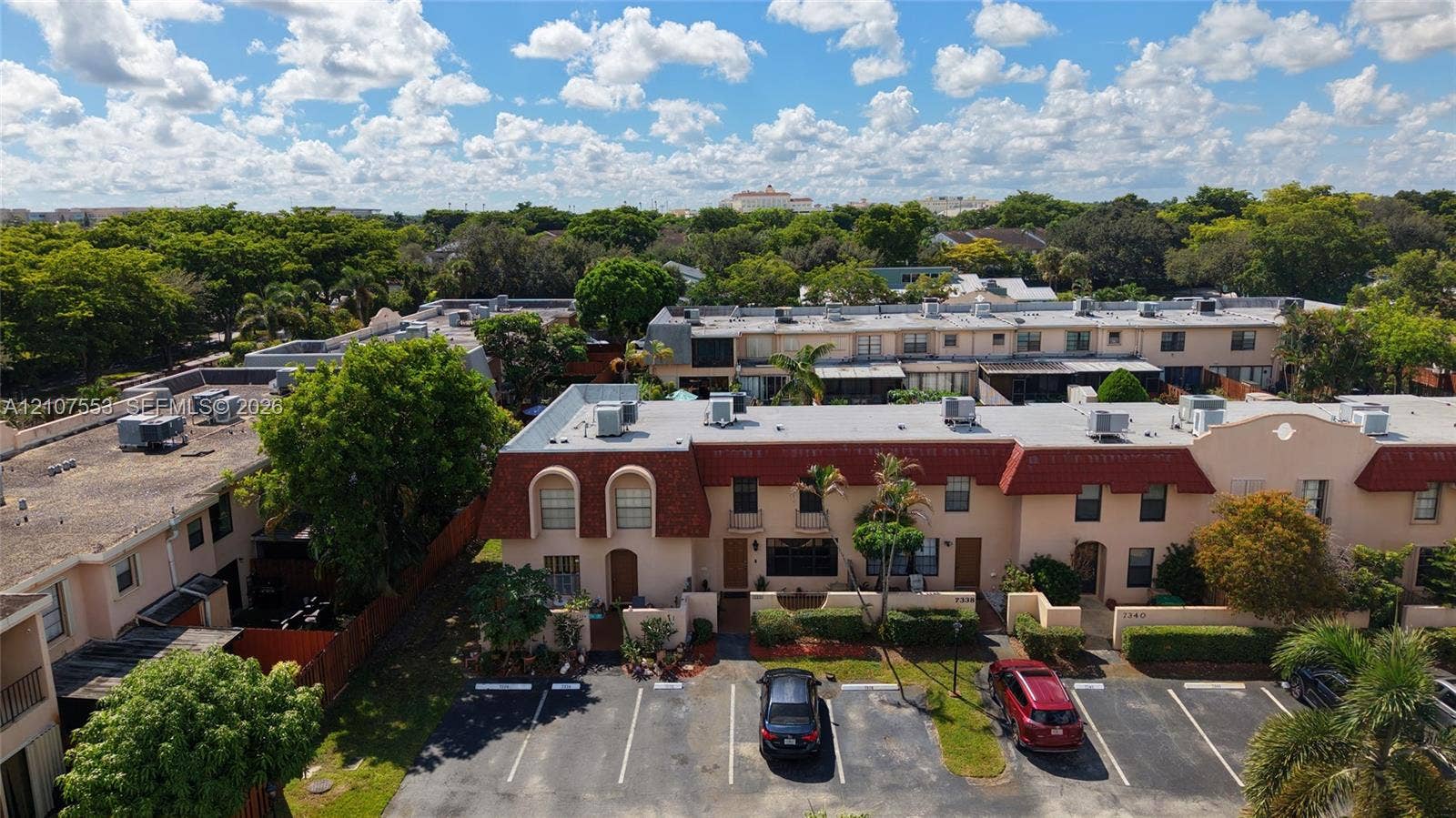 7336 SW 26th Court, #51, Davie, Davie, FL 33314 Multi-level townhome exterior featuring a red mansard roof, stucco facade, private enclosed entryway, dedicated surface parking, and mature landscaping