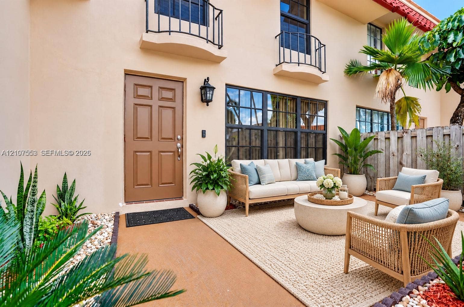 7336 SW 26th Court, #51, Davie, Davie, FL 33314 Stucco exterior featuring dual upper-level metal balconies, a multi-pane grid window, six-panel entry door, and a paved courtyard