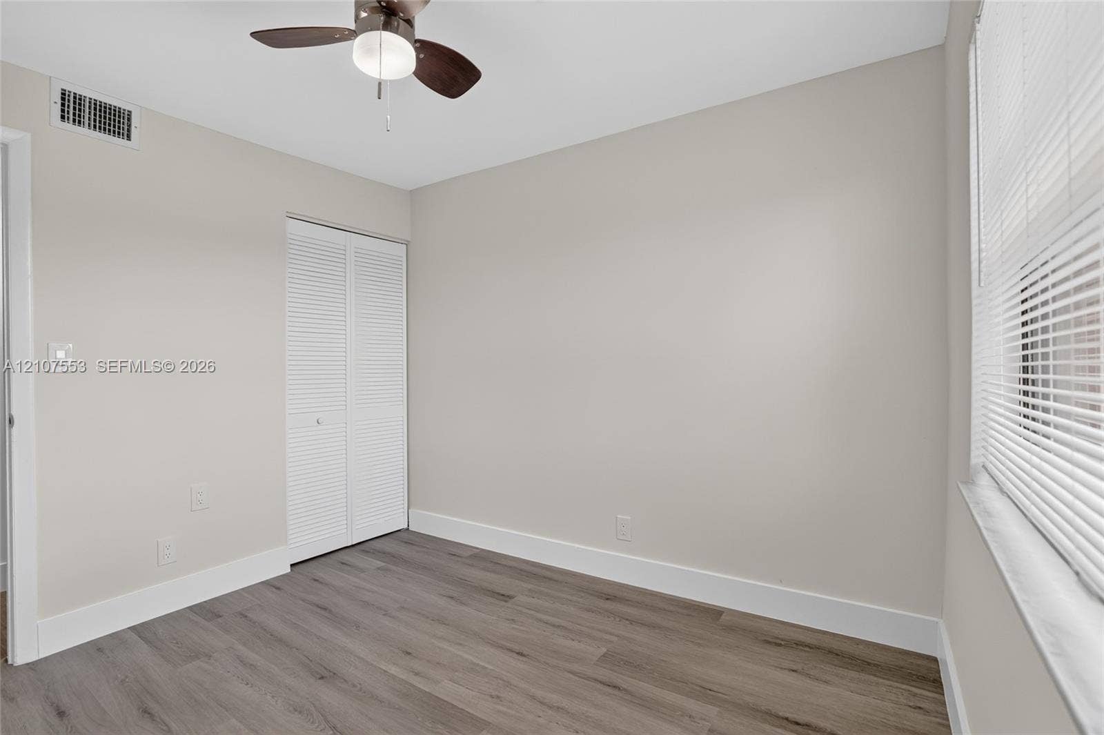 7336 SW 26th Court, #51, Davie, Davie, FL 33314 Neutral-toned room featuring wood-finish flooring, a ceiling fan with integrated lighting, and a bi-fold closet
