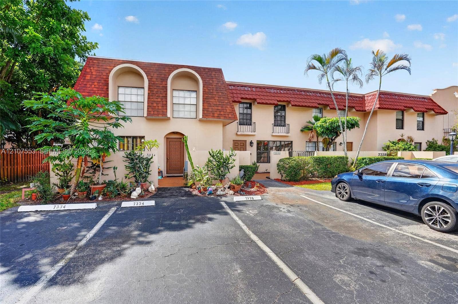 7336 SW 26th Court, #51, Davie, Davie, FL 33314 Two-story exterior featuring a mansard roof with shingle tiles, arched window detailing, stucco facade, and dedicated assigned parking spaces