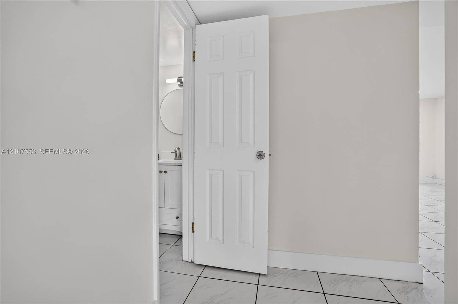 7336 SW 26th Court, #51, Davie, Davie, FL 33314 Six-panel interior door with brushed nickel hardware, leading to a vanity area featuring a round mirror, integrated sink, and polished chrome faucet