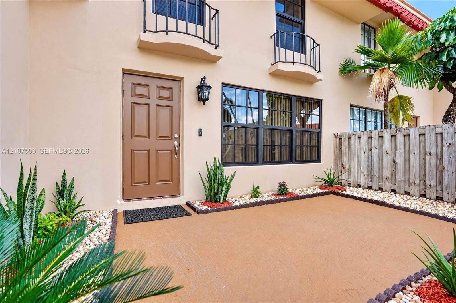 7336 SW 26th Court, #51, Davie, Davie, FL 33314 Stucco exterior featuring dual upper-level balconies with metal railings, a multi-pane grid window, and a paved front patio with decorative stone borders