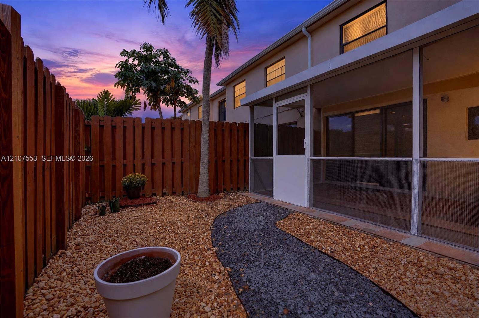 7336 SW 26th Court, #51, Davie, Davie, FL 33314 Screened-in patio with concrete flooring, stone-grounded yard, wood privacy fencing, and palm tree