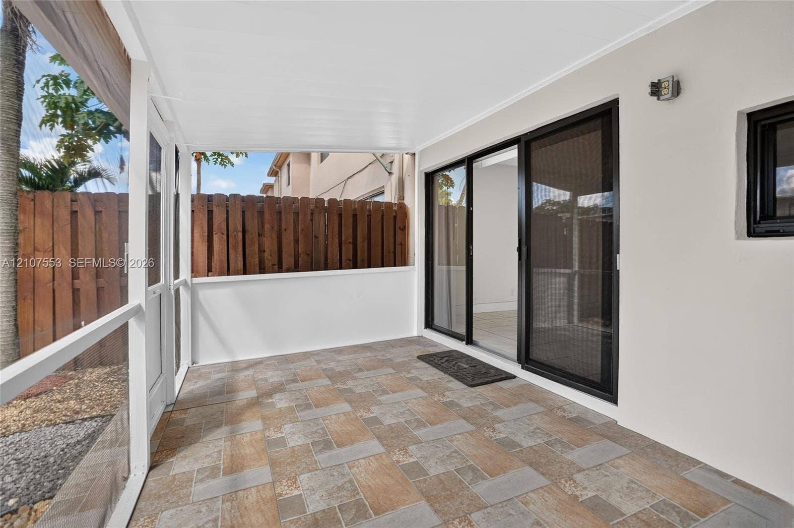 7336 SW 26th Court, #51, Davie, Davie, FL 33314 Screened-in patio featuring patterned tile flooring, a solid white ceiling, a white privacy enclosure, and a sliding glass door entry