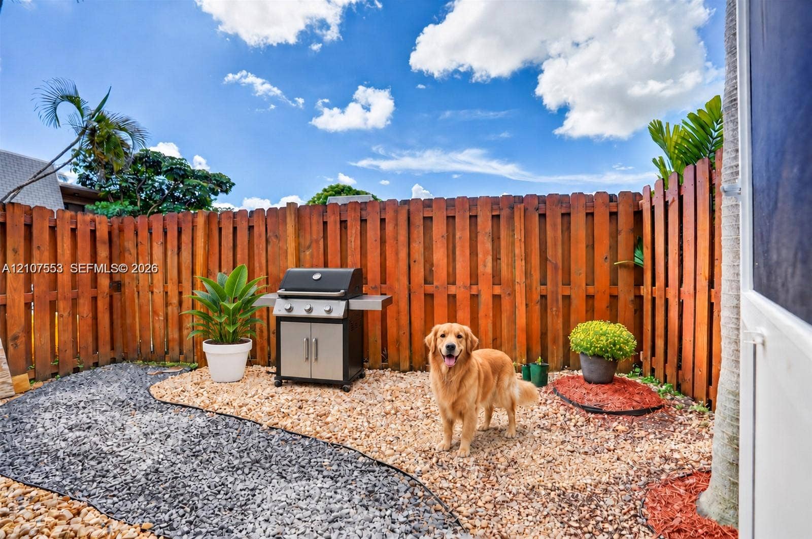 7336 SW 26th Court, #51, Davie, Davie, FL 33314 Private courtyard featuring a high wood privacy fence, decorative gravel landscaping, and a built-in outdoor cooking station