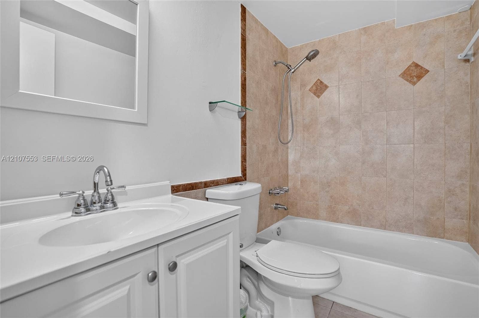 7336 SW 26th Court, #51, Davie, Davie, FL 33314 White vanity with integrated basin and polished metal faucet, complemented by a bathtub with a handheld shower head and tiled surround featuring decorative accents