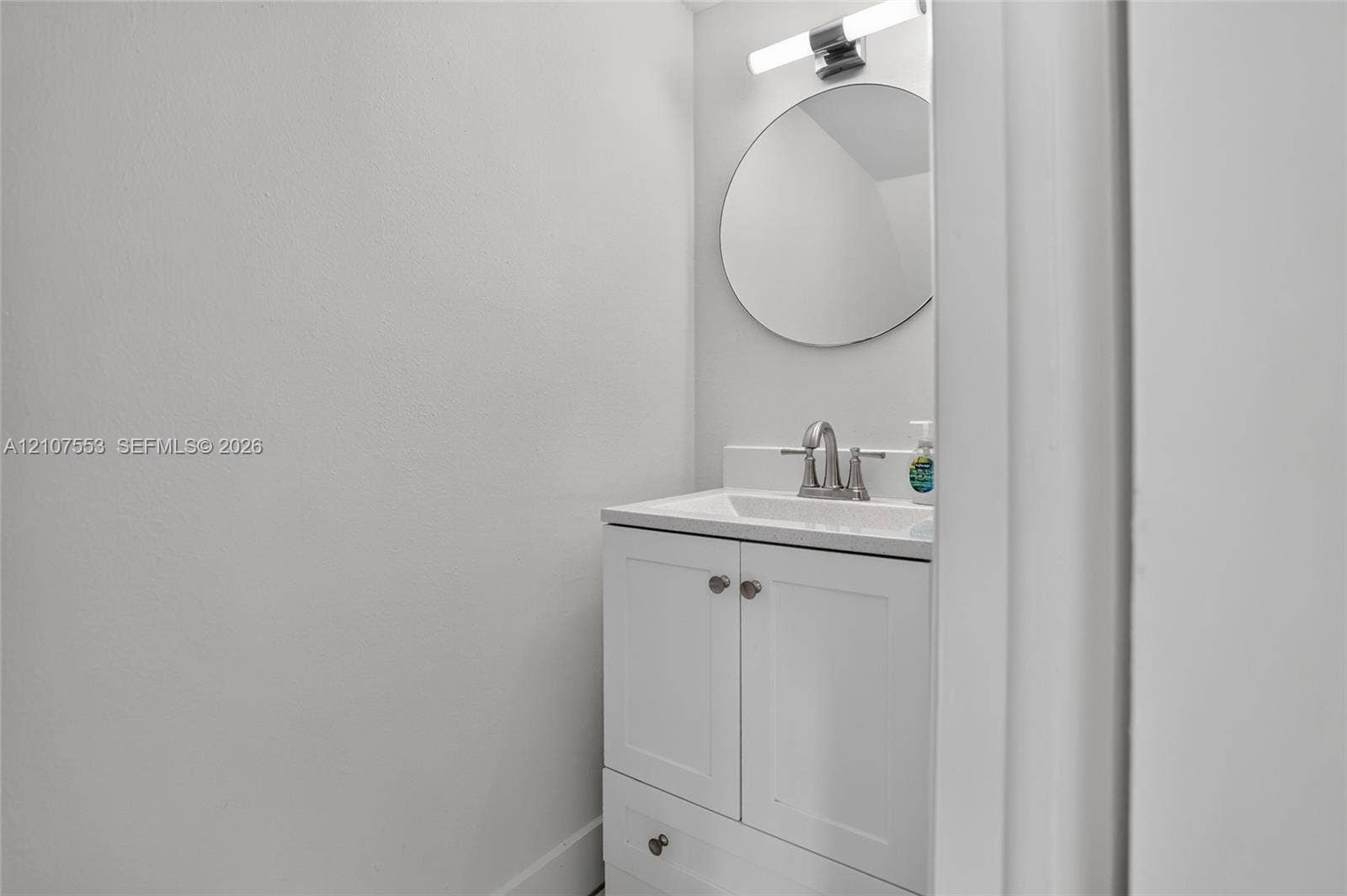7336 SW 26th Court, #51, Davie, Davie, FL 33314 Shaker-style white vanity with a rectangular sink, satin-nickel faucet, circular wall mirror, and modern linear light fixture