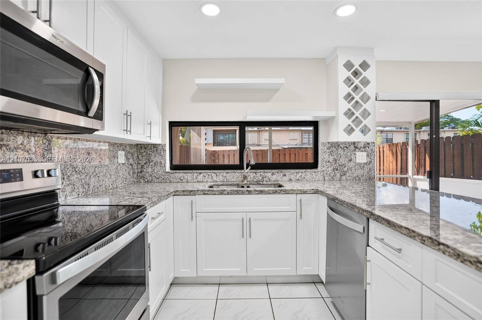 7336 SW 26th Court, #51, Davie, Davie, FL 33314 Kitchen featuring white shaker-style cabinetry, stone countertops with matching backsplash, built-in wine rack, stainless steel appliances, and tile flooring