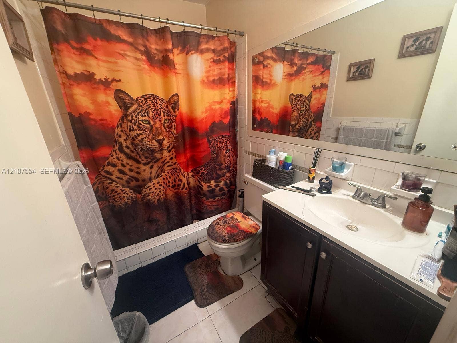 Bathroom featuring a vanity with a white countertop and oval basin, tile surround shower, large wall-mounted mirror, and white floor tile