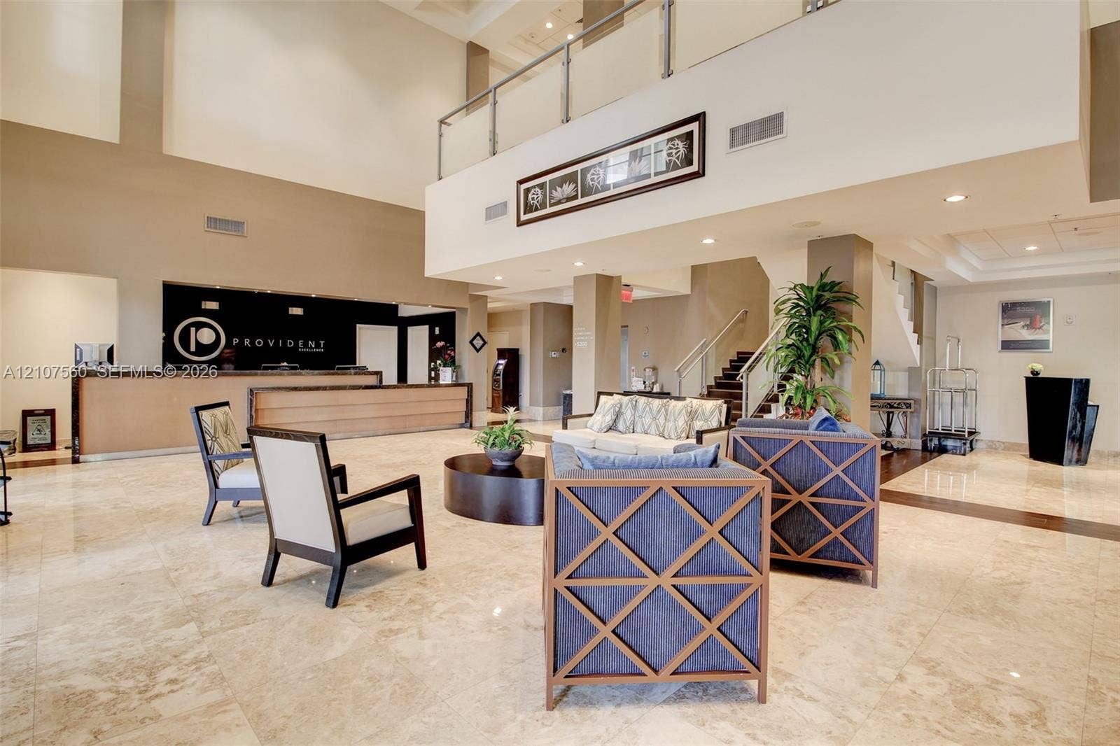5300 NW 87th Avenue, #407, Doral, FL 33178 Expansive lobby featuring vaulted ceilings, polished stone flooring, a built-in reception desk, and a mezzanine level with glass and metal railings