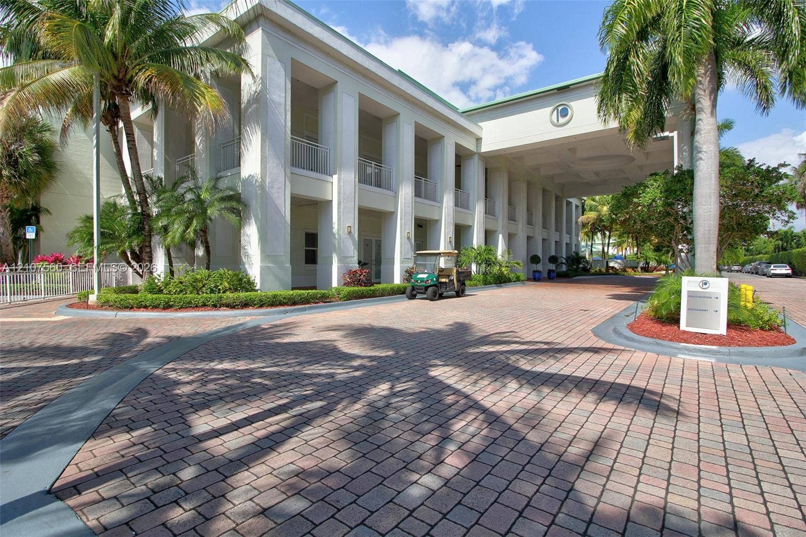 5300 NW 87th Avenue, #407, Doral, FL 33178 Multi-story exterior featuring a grand porte-cochre, prominent architectural columns, covered balconies, and a paver stone motor court