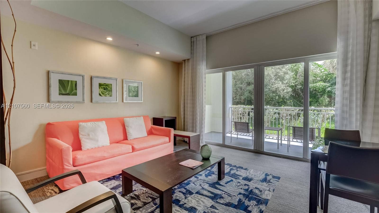 5300 NW 87th Avenue, #407, Doral, FL 33178 Living area featuring high ceilings, recessed lighting, and expansive sliding glass doors providing access to a covered balcony with metal railing
