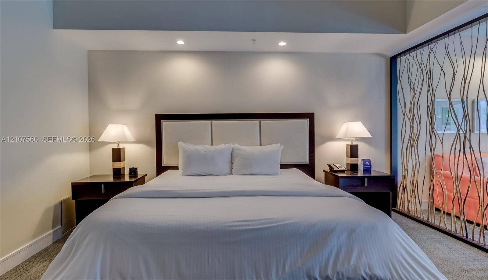 5300 NW 87th Avenue, #407, Doral, FL 33178 Built-in rectangular headboard with upholstered paneling and decorative room divider featuring an organic branch-inspired screen