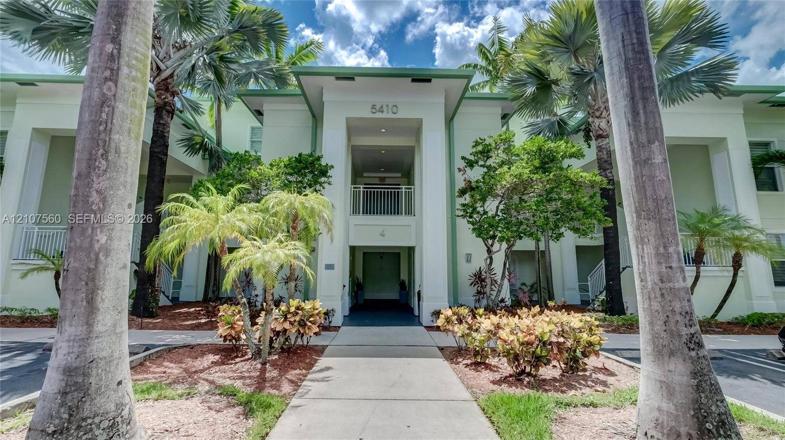 5300 NW 87th Avenue, #407, Doral, FL 33178 Multi-story exterior featuring a covered entryway, concrete walkway, and mature palm landscaping