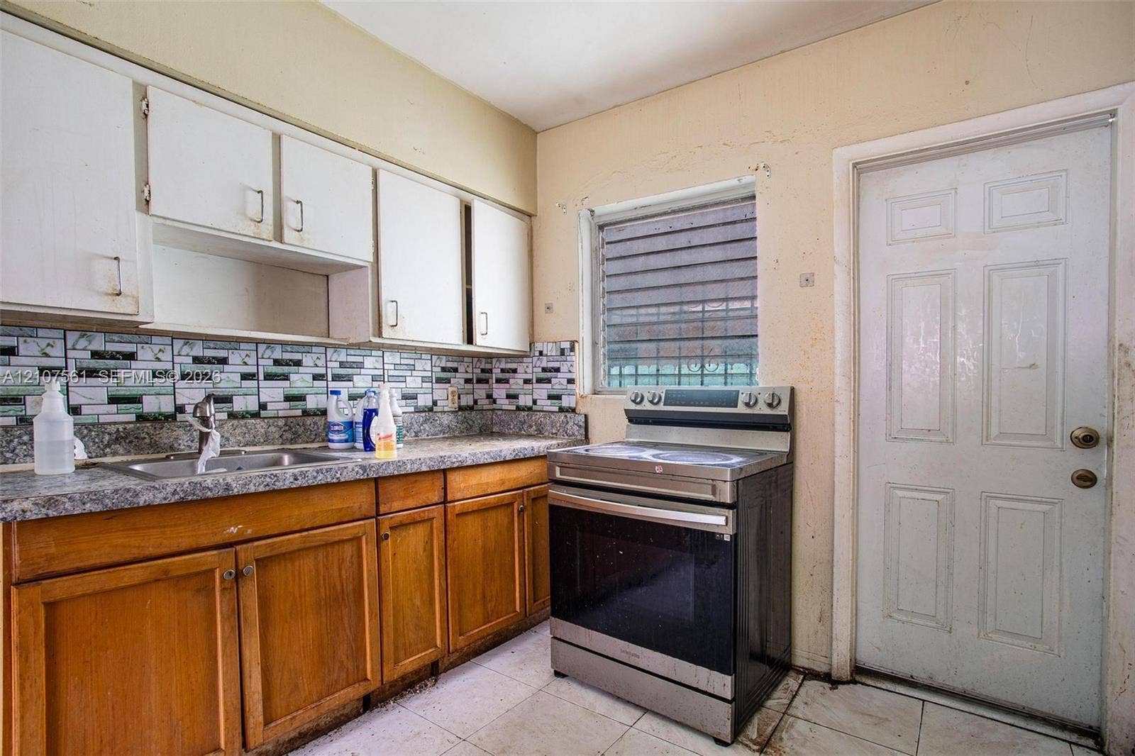50 NW 69th Street, Miami, FL 33150 Kitchen featuring wood cabinetry, stone-finish countertops, decorative tile backsplash, stainless steel electric range, and tile flooring