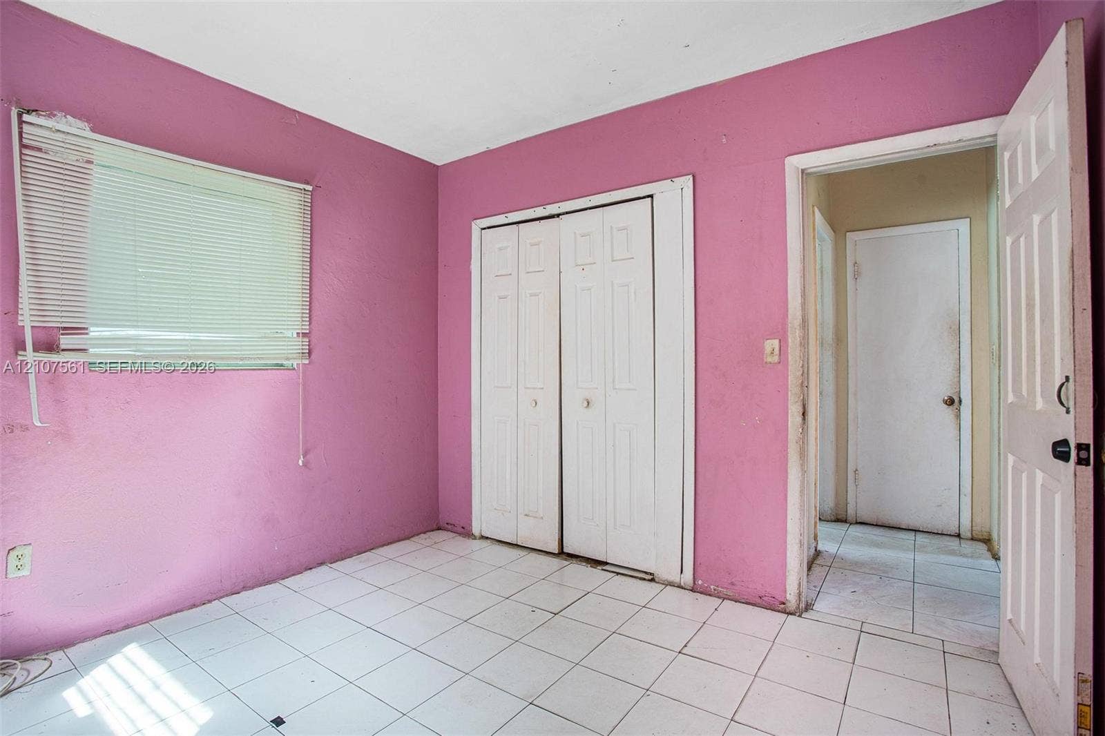 50 NW 69th Street, Miami, FL 33150 Room featuring white tile flooring, white bi-fold closet doors, and white interior doors with hardware