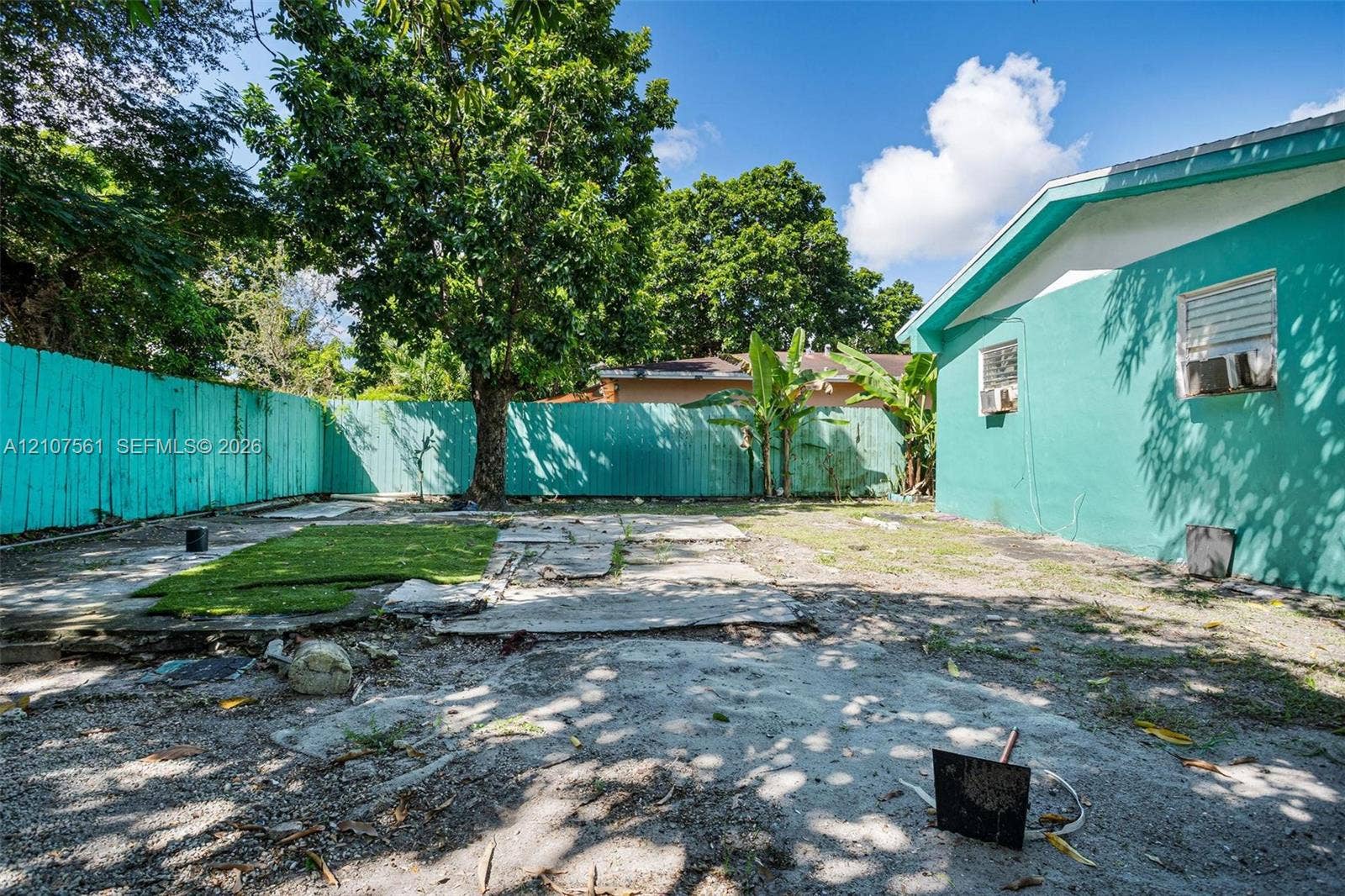 50 NW 69th Street, Miami, FL 33150 Fenced backyard featuring mature trees, partial synthetic turf, and hardscape areas
