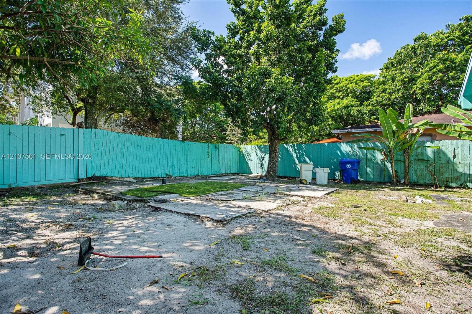 50 NW 69th Street, Miami, FL 33150 Backyard featuring a wood-panel perimeter fence, stone paver pathway, and mature tree canopy