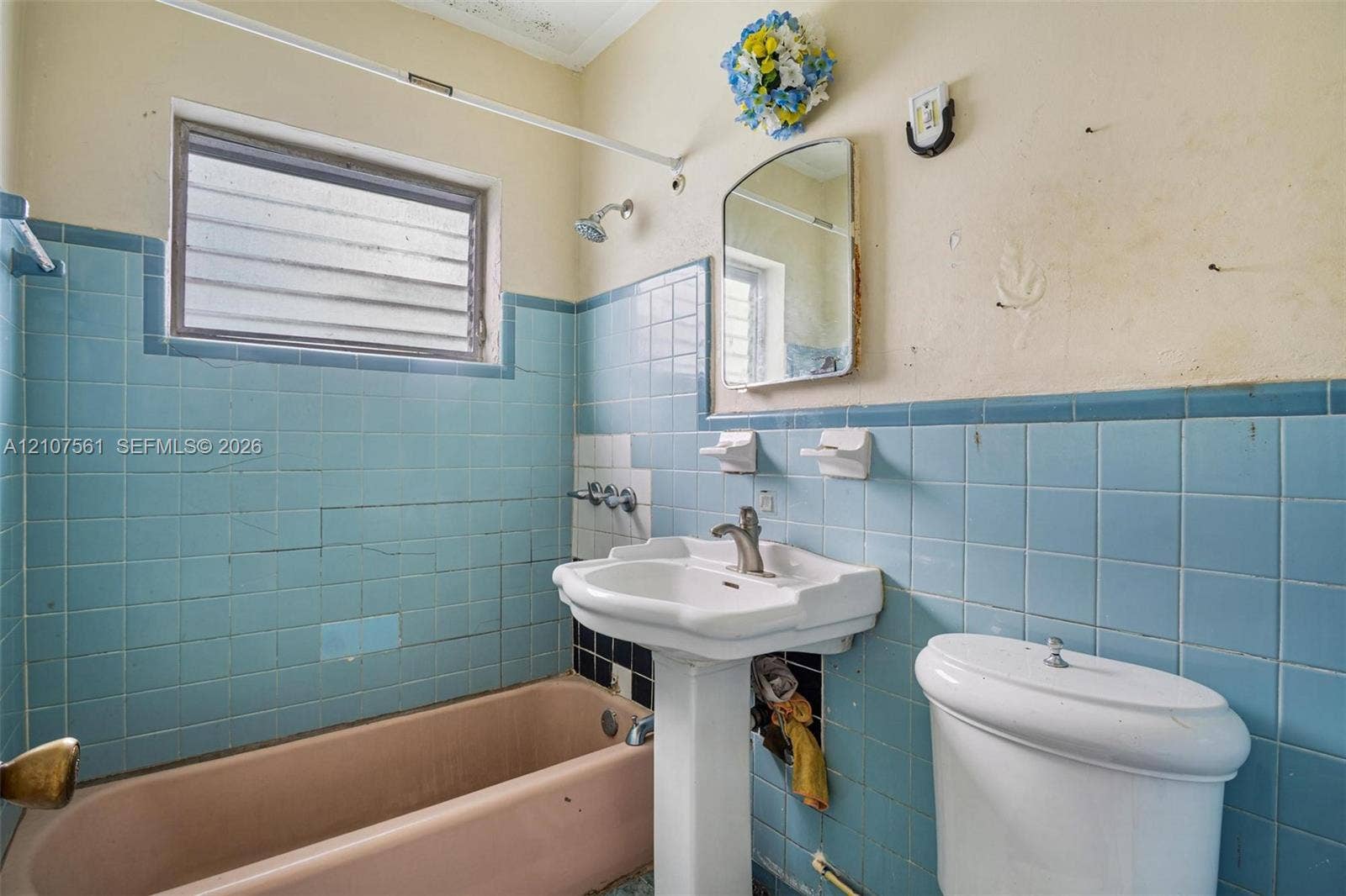 50 NW 69th Street, Miami, FL 33150 Bathroom featuring blue ceramic wall tiling, a pedestal sink with a chrome faucet, a rectangular jetted tub, and a louvered window
