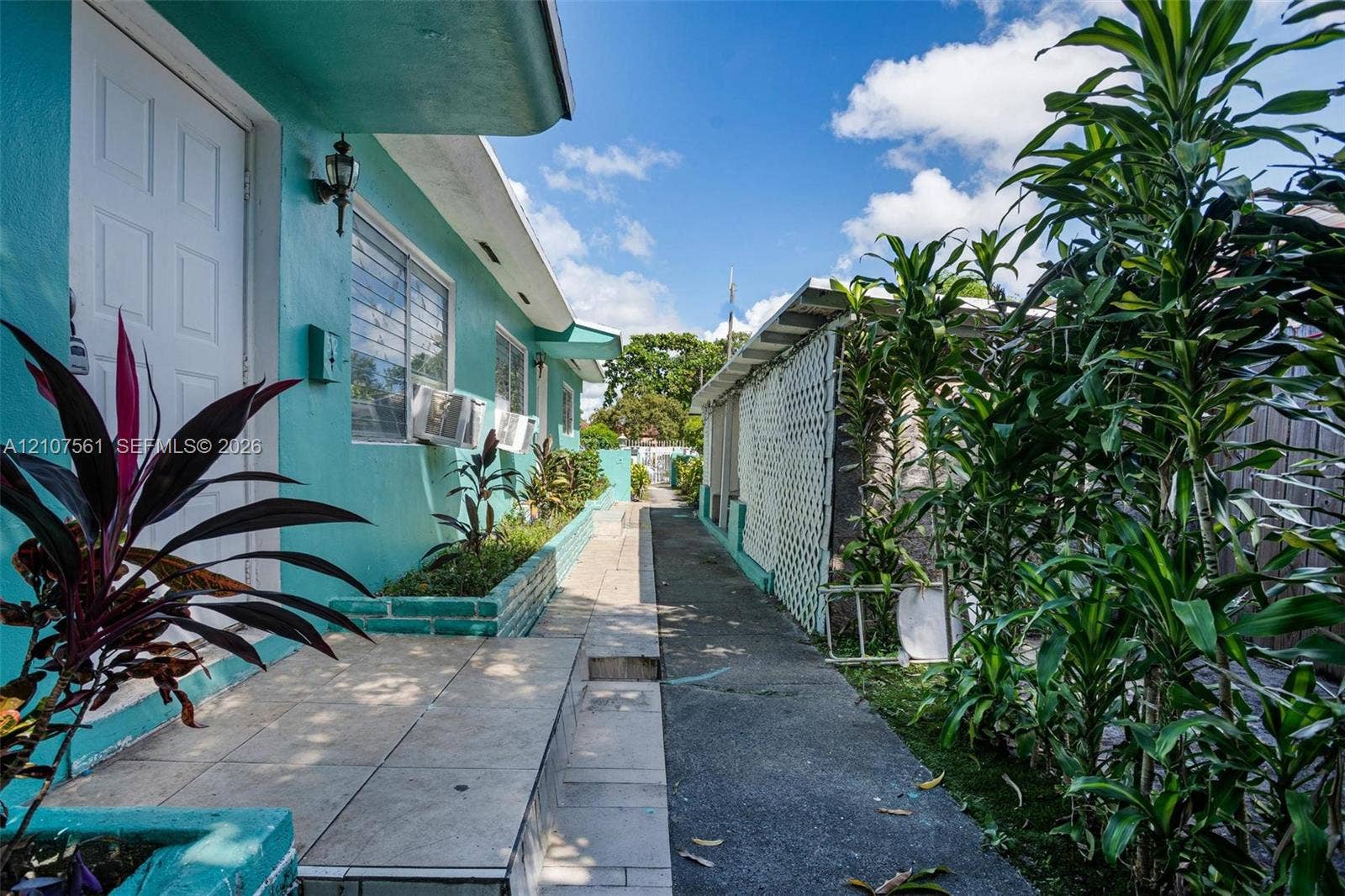 50 NW 69th Street, Miami, FL 33150 Exterior pathway featuring a tiled entryway, masonry planter boxes, and white lattice fencing