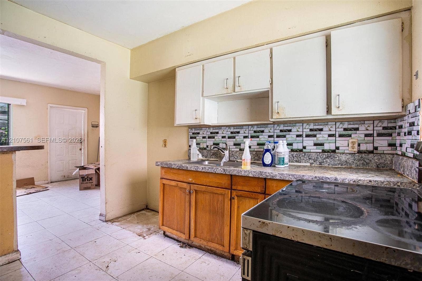 50 NW 69th Street, Miami, FL 33150 Kitchen featuring wood cabinetry, stone-finish countertops, tile backsplash, and a ceramic cooktop