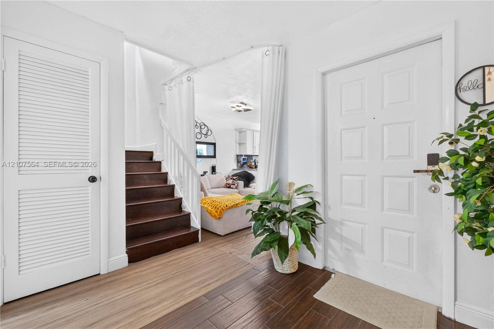 Foyer featuring a six-panel entry door, louvered-style closet door, staircase with dark wood-finished treads, and dual-tone flooring