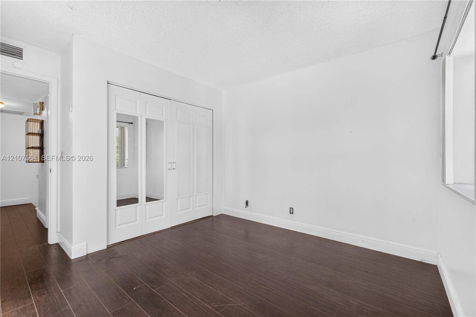 Wood-finish flooring and double-door closet with inset mirror panels