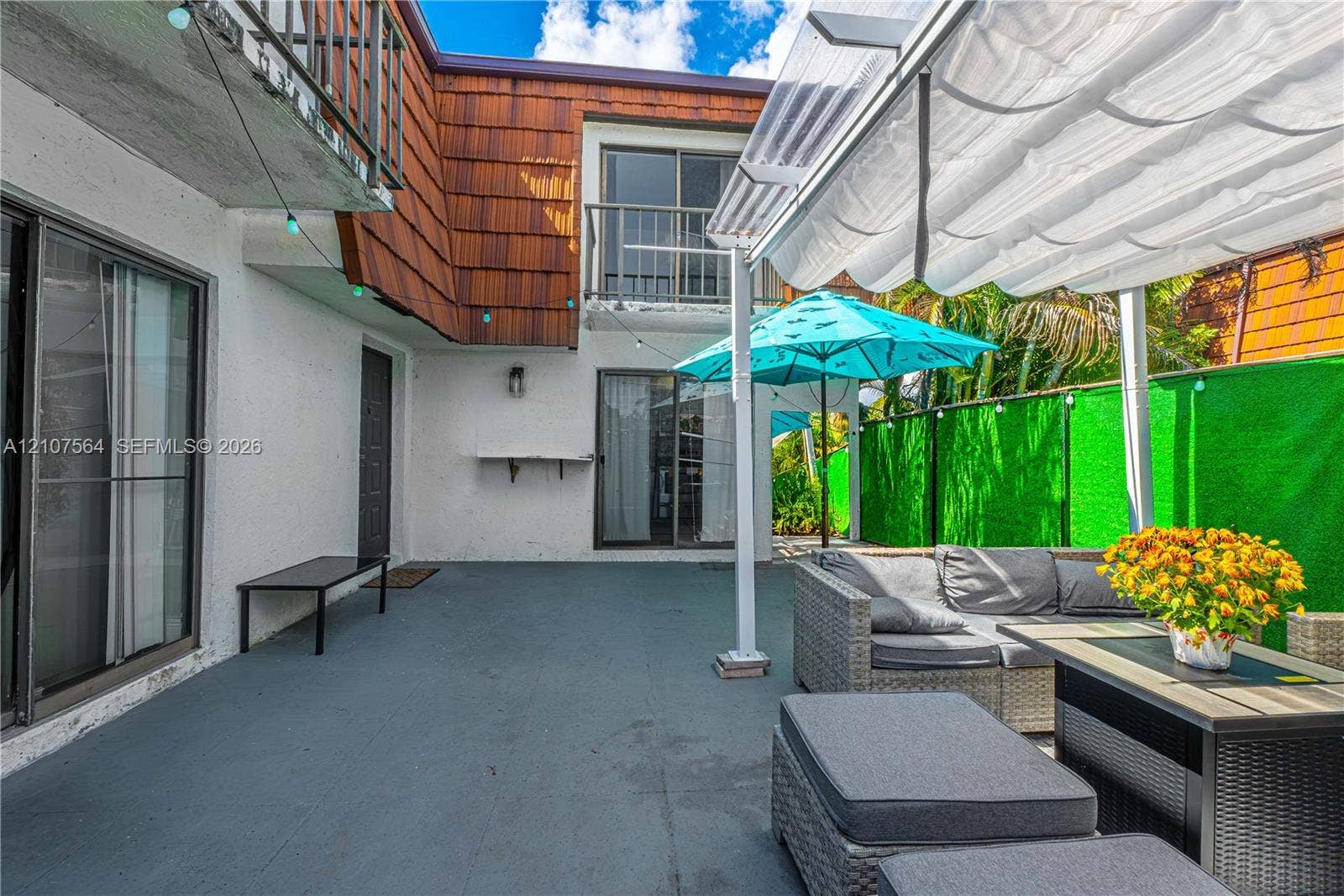 Outdoor patio featuring a covered pergola structure, balcony access, sliding glass door entrances, and wood-shake exterior accents
