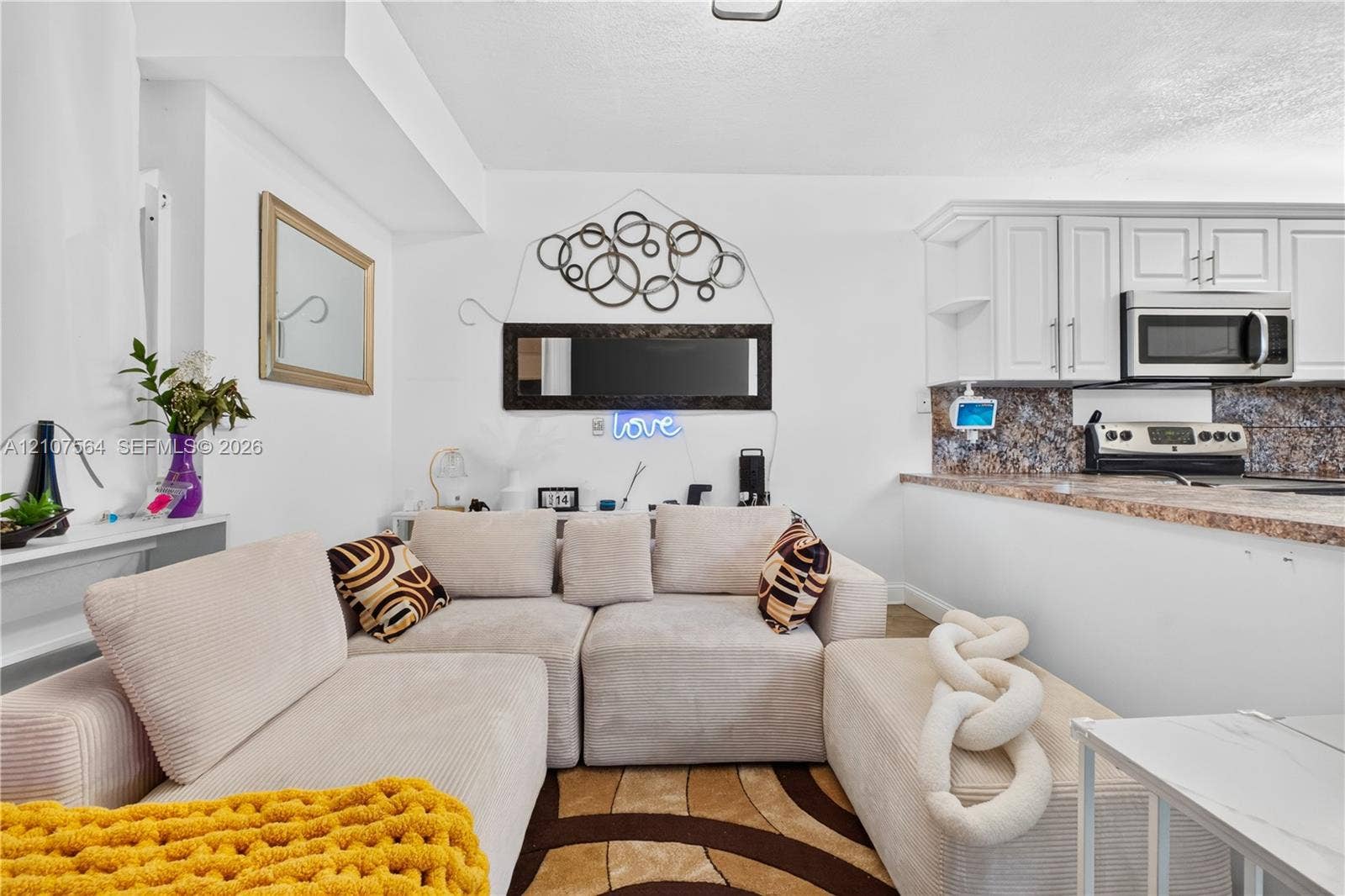 Kitchen featuring white shaker-style cabinetry, a stone-patterned laminate countertop, a tiled backsplash, and an integrated stainless steel microwave