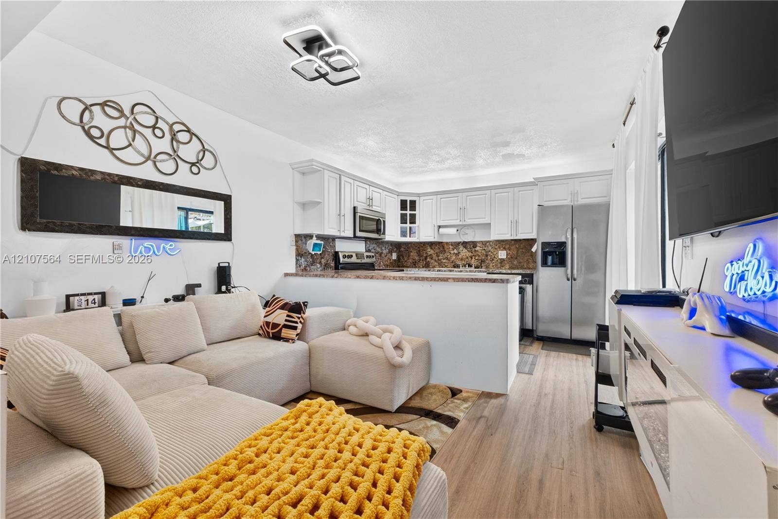 Kitchen featuring white cabinetry, stone-finish countertops, stainless steel appliances, wood-finish flooring, and a modern geometric flush-mount light fixture