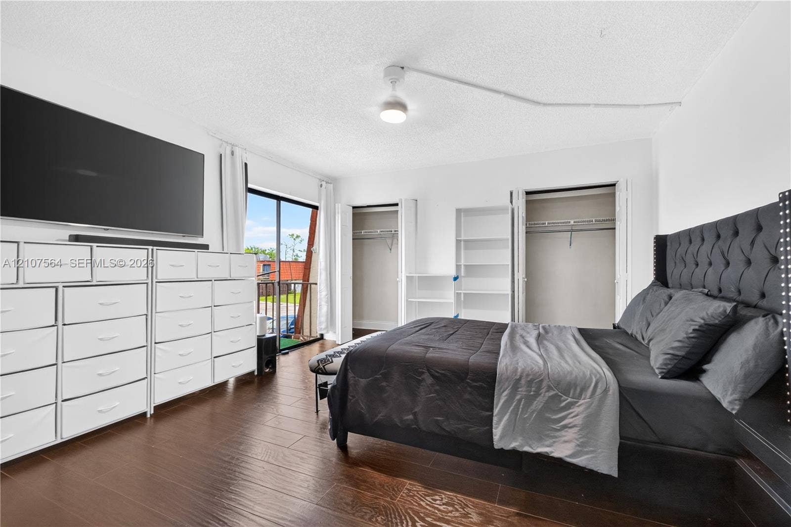 Wood-finish flooring, sliding glass door, dual reach-in closets, built-in shelving, and ceiling-mounted light fixture