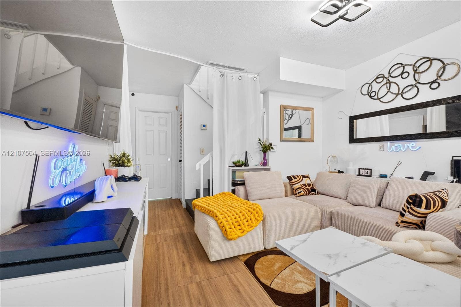 Interior space featuring wood-finish flooring, white paneled interior doors, and geometric flush-mount ceiling lighting