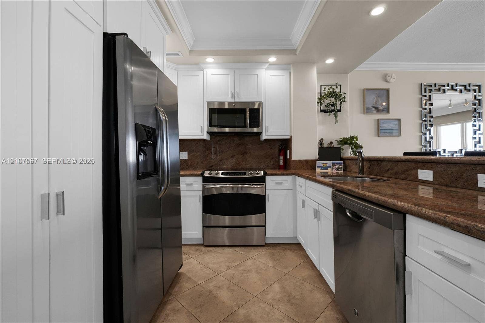 Kitchen featuring white shaker-style cabinetry, stainless steel appliances, stone-surface countertops, and tiled flooring